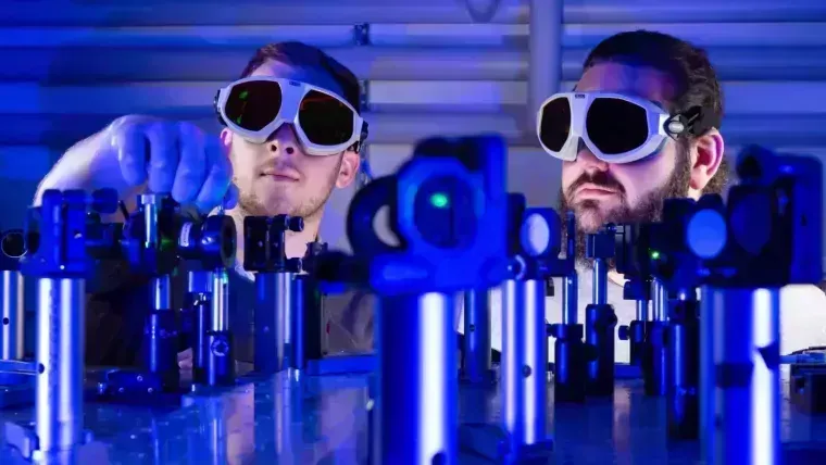 The doctoral candidates Paul Herrmann (l.) and Sebastian Klimmer during the construction of a laser experiment.